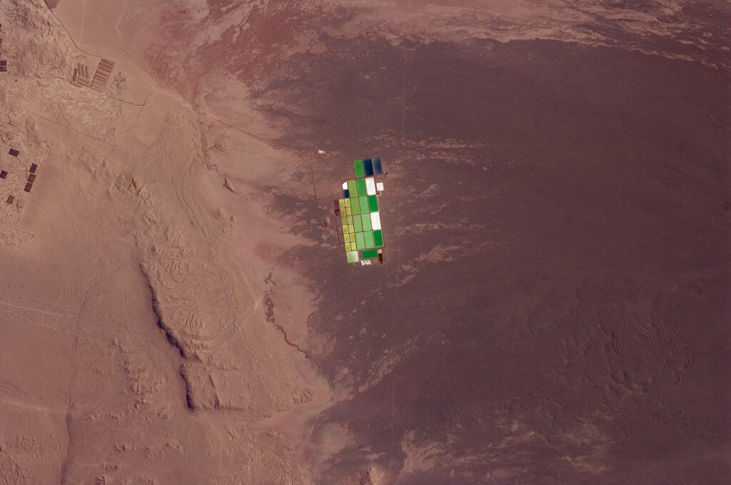 Brightly coloured solar evaporation (salt) ponds in a desert landscape give this astronaut photo an unreal quality. The